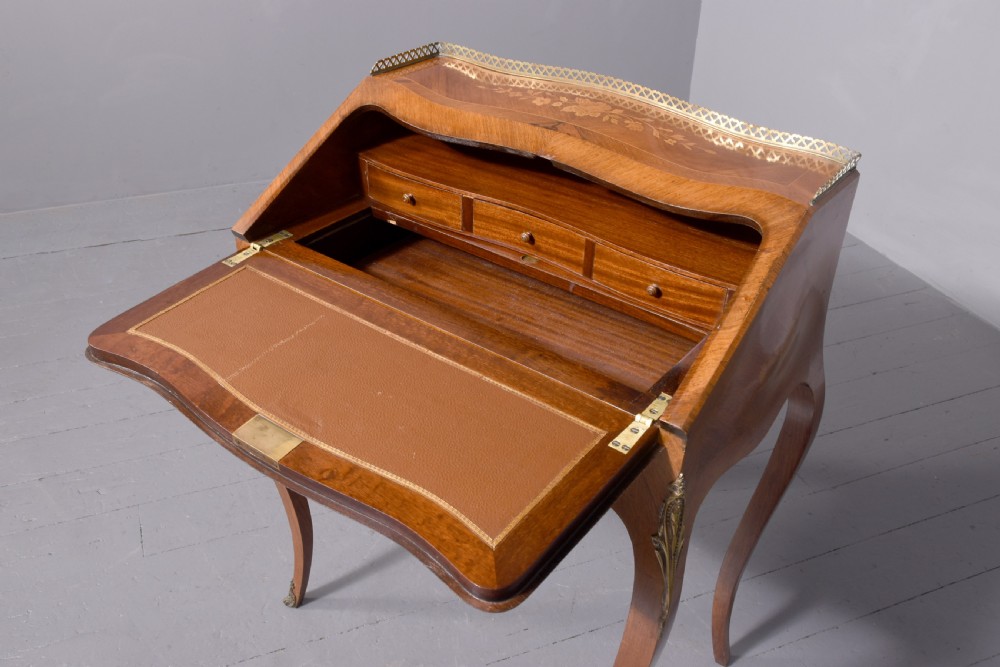 A small French Louis XV style slope-front writing desk featuring floral marquetry inlays, cabriole legs with brass mounts, and a brass gallery rail. View XI