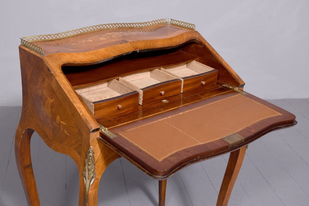 A small French Louis XV style slope-front writing desk featuring floral marquetry inlays, cabriole legs with brass mounts, and a brass gallery rail. View XII
