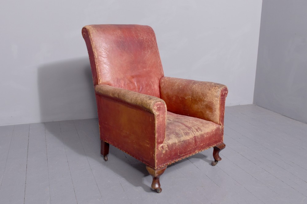 A pair of deep red leather library armchairs with high backs, rolled arms, brass stud trimming, and turned wooden front legs on castors. View VI