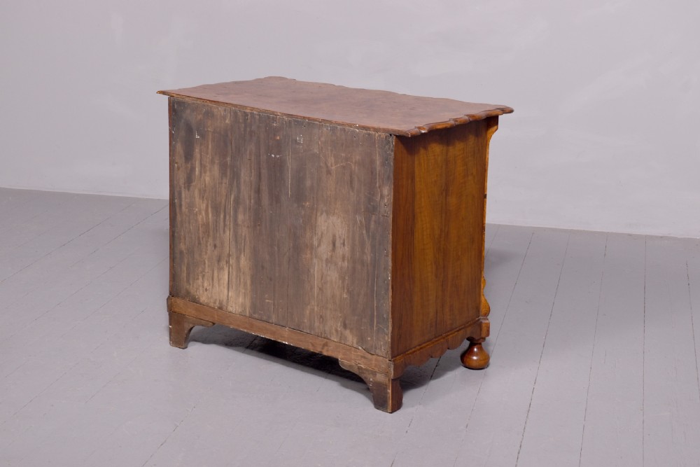 An eighteenth-century Dutch burr elm chest of drawers featuring a contoured front, four long drawers with brass drop handles, and turned bun feet. View II