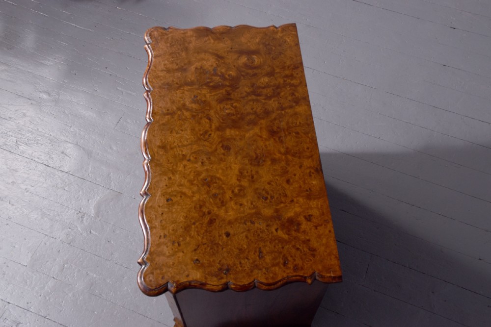 An eighteenth-century Dutch burr elm chest of drawers featuring a contoured front, four long drawers with brass drop handles, and turned bun feet. View III