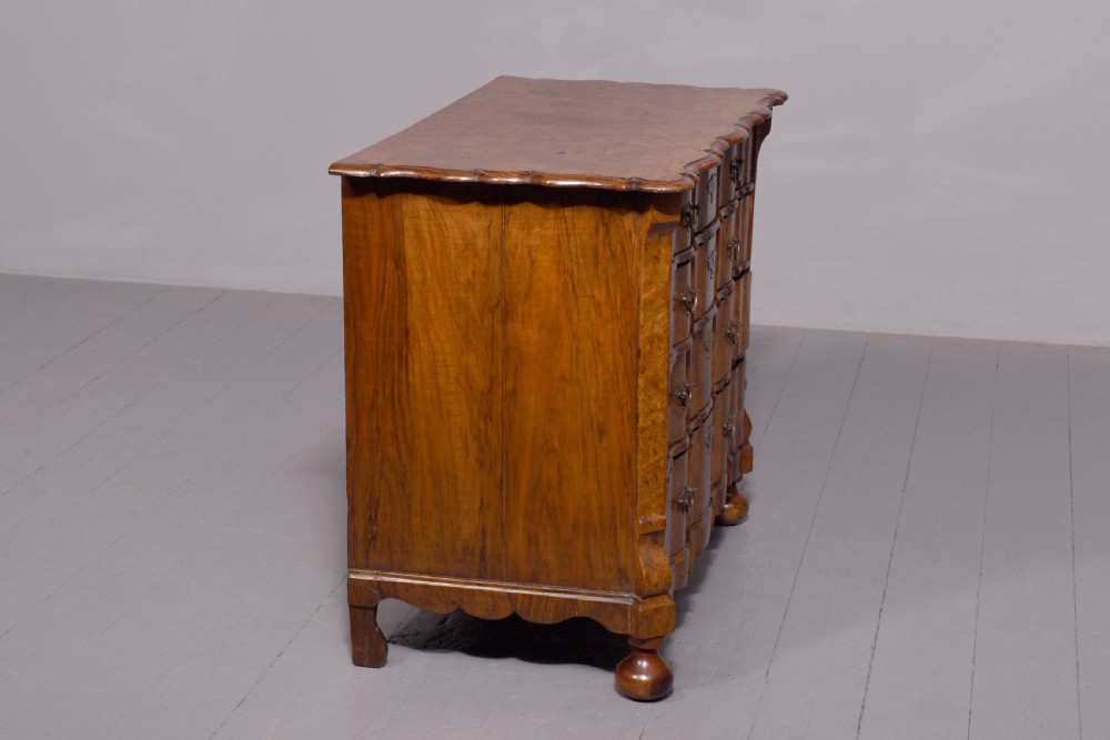 An eighteenth-century Dutch burr elm chest of drawers featuring a contoured front, four long drawers with brass drop handles, and turned bun feet. View V