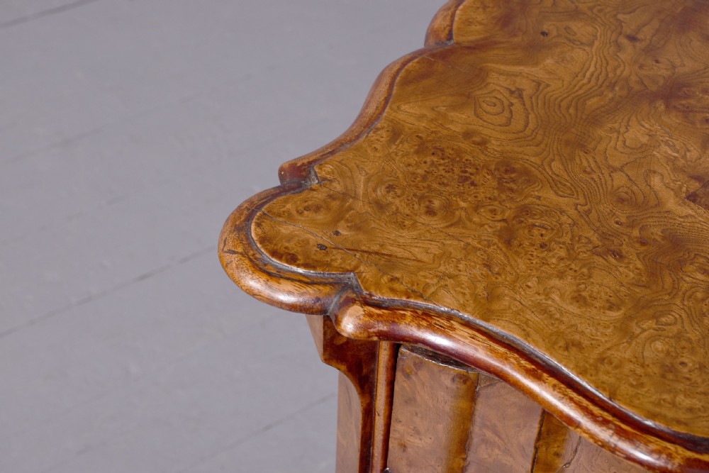 An eighteenth-century Dutch burr elm chest of drawers featuring a contoured front, four long drawers with brass drop handles, and turned bun feet. View IX
