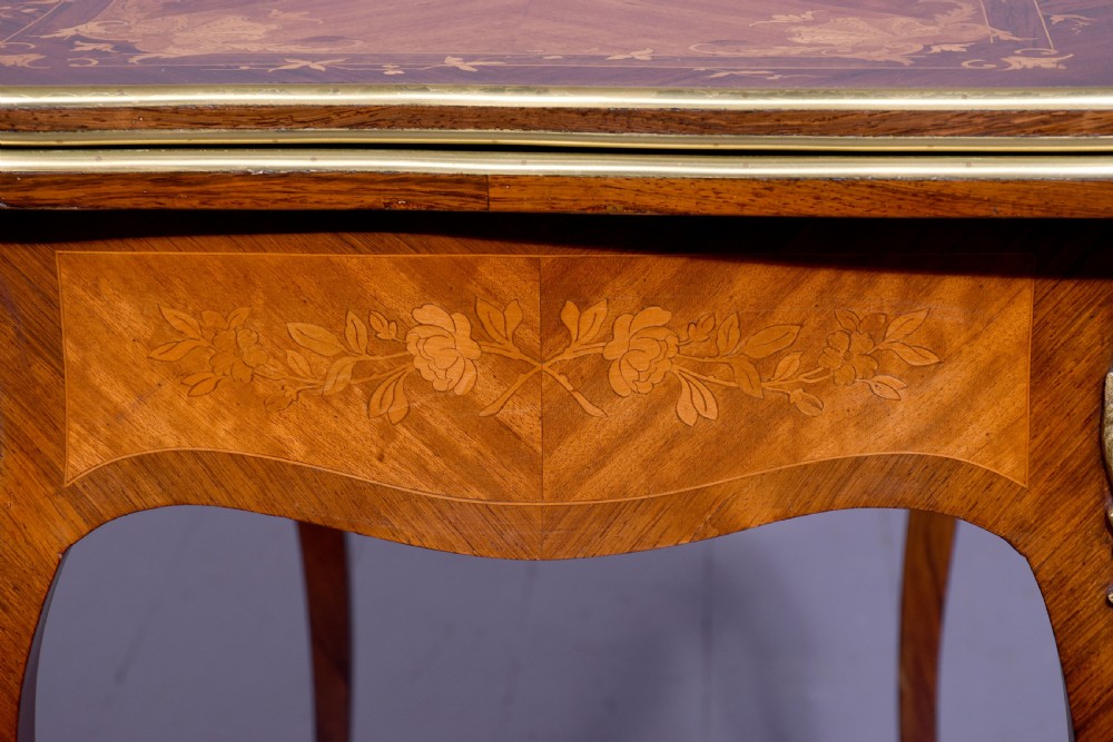 A Louis XV style French fold-over card table featuring warm brown veneer with floral marquetry inlay, cabriole legs, and gilt-bronze mounts. View III
