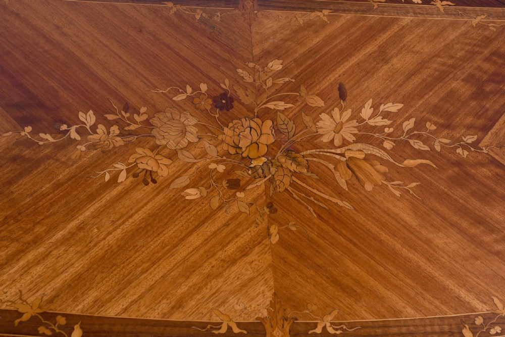 A Louis XV style French fold-over card table featuring warm brown veneer with floral marquetry inlay, cabriole legs, and gilt-bronze mounts. View XV