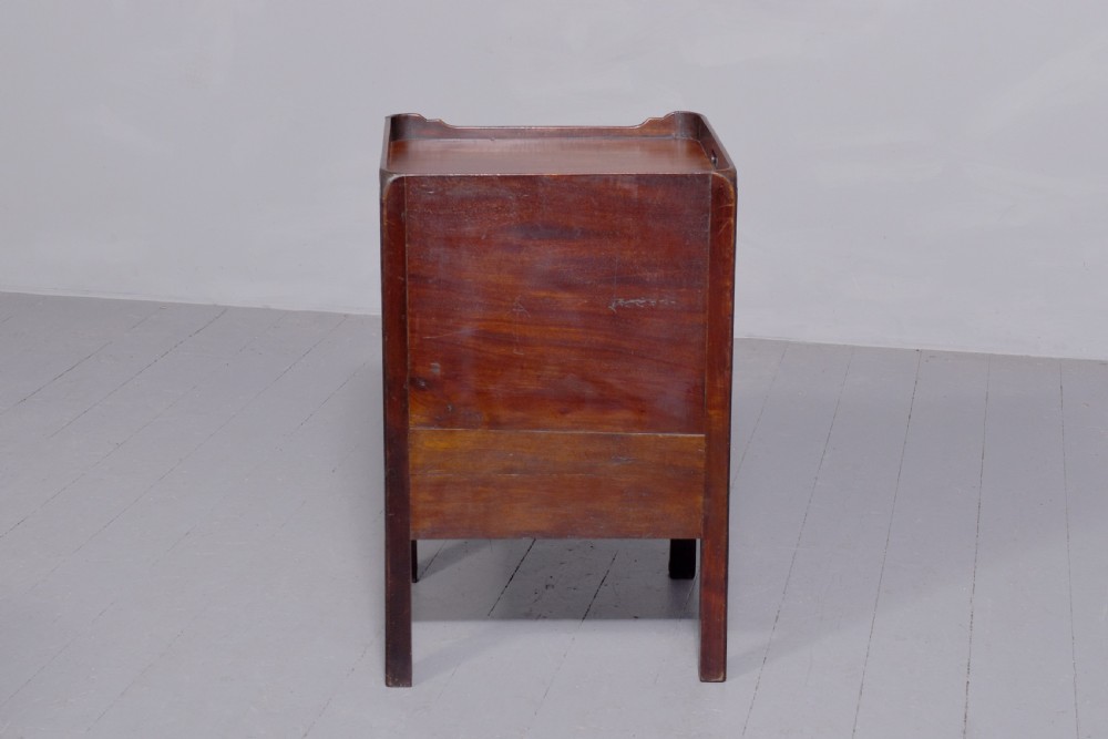 A George III mahogany tray top bedside commode featuring a raised gallery with handles, two cupboard doors, and a lower drawer with a brass bail handle. View II