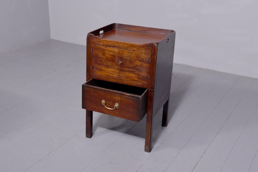 A George III mahogany tray top bedside commode featuring a raised gallery with handles, two cupboard doors, and a lower drawer with a brass bail handle. View III