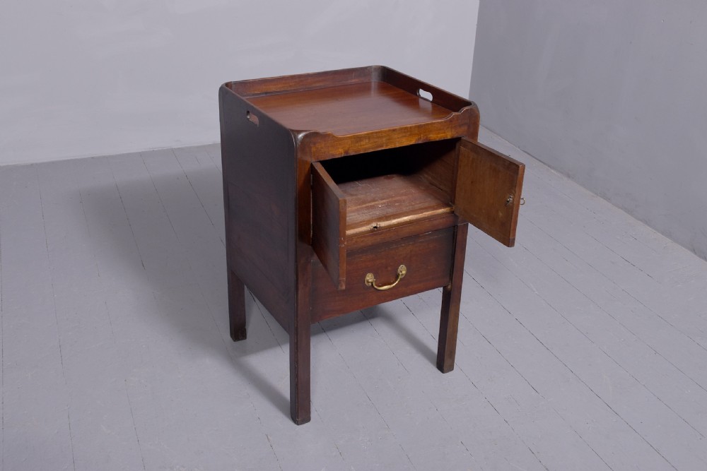 A George III mahogany tray top bedside commode featuring a raised gallery with handles, two cupboard doors, and a lower drawer with a brass bail handle. View IV