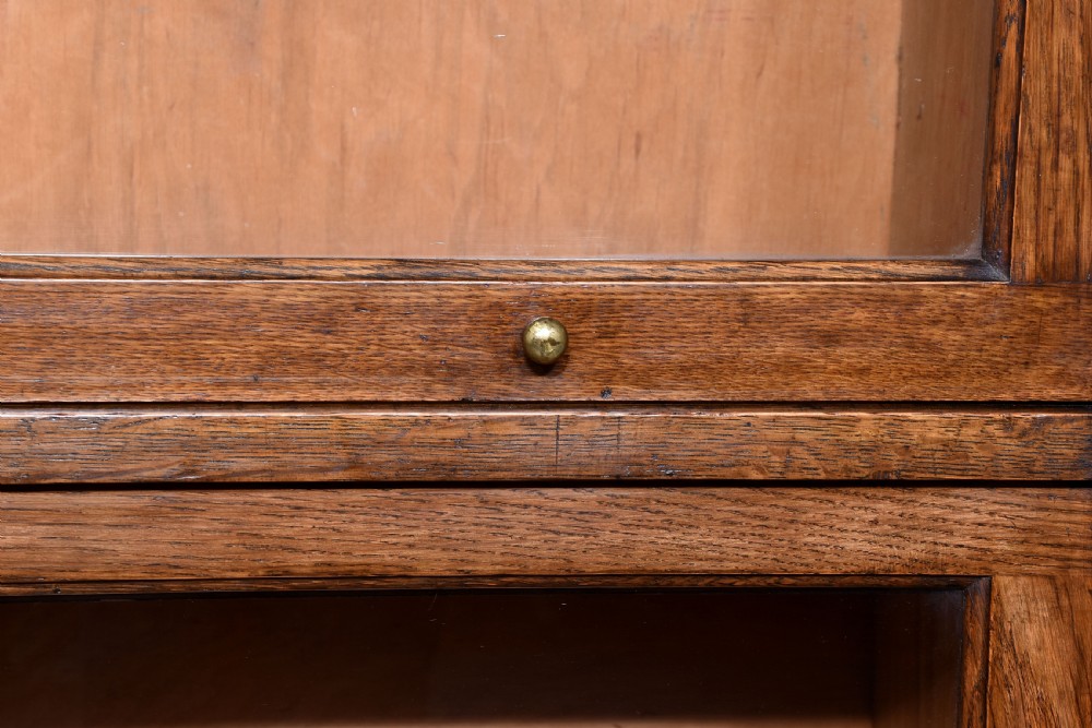 A four-tier Edwardian oak sectional bookcase featuring glazed up-and-over doors, brass handles, and an arched gallery top rail. View IV
