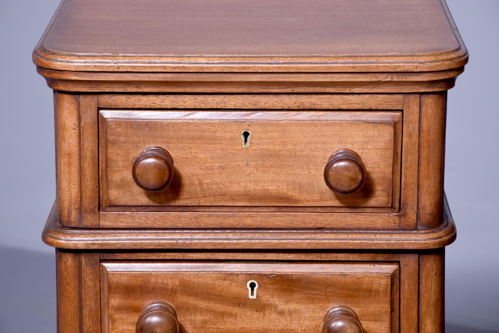 A pair of tall Victorian mahogany Wellington-style chests, each featuring five stacked drawers with turned wood knobs and stepped plinth bases. View VI