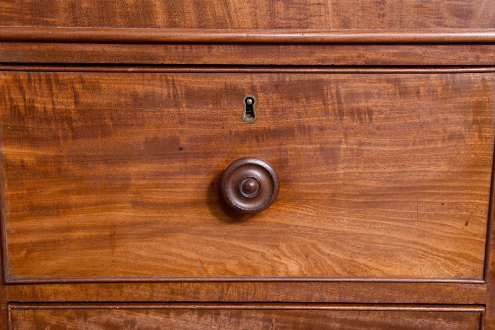 A nineteenth-century mahogany low linen press featuring two central panelled doors flanked by four drawers on each side, set on a solid plinth base. View II