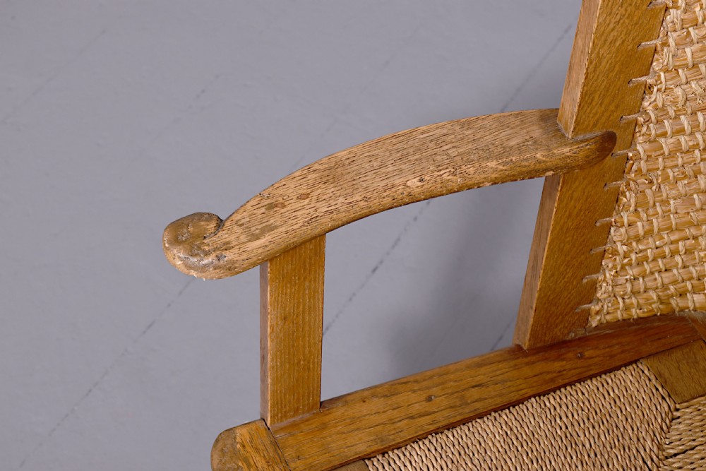 An oak armchair featuring a tall woven straw backrest, flat open armrests, and a rush seat. View II
