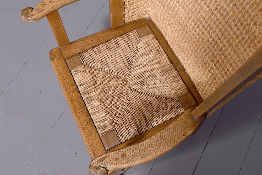 An oak armchair featuring a tall woven straw backrest, flat open armrests, and a rush seat. View III