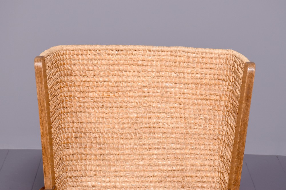 An oak armchair featuring a tall woven straw backrest, flat open armrests, and a rush seat. View V