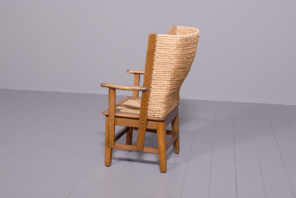 An oak armchair featuring a tall woven straw backrest, flat open armrests, and a rush seat. View VII