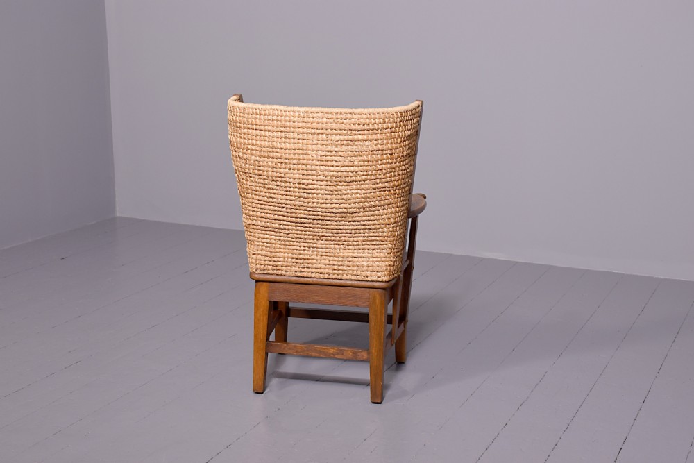 An oak armchair featuring a tall woven straw backrest, flat open armrests, and a rush seat. View VIII