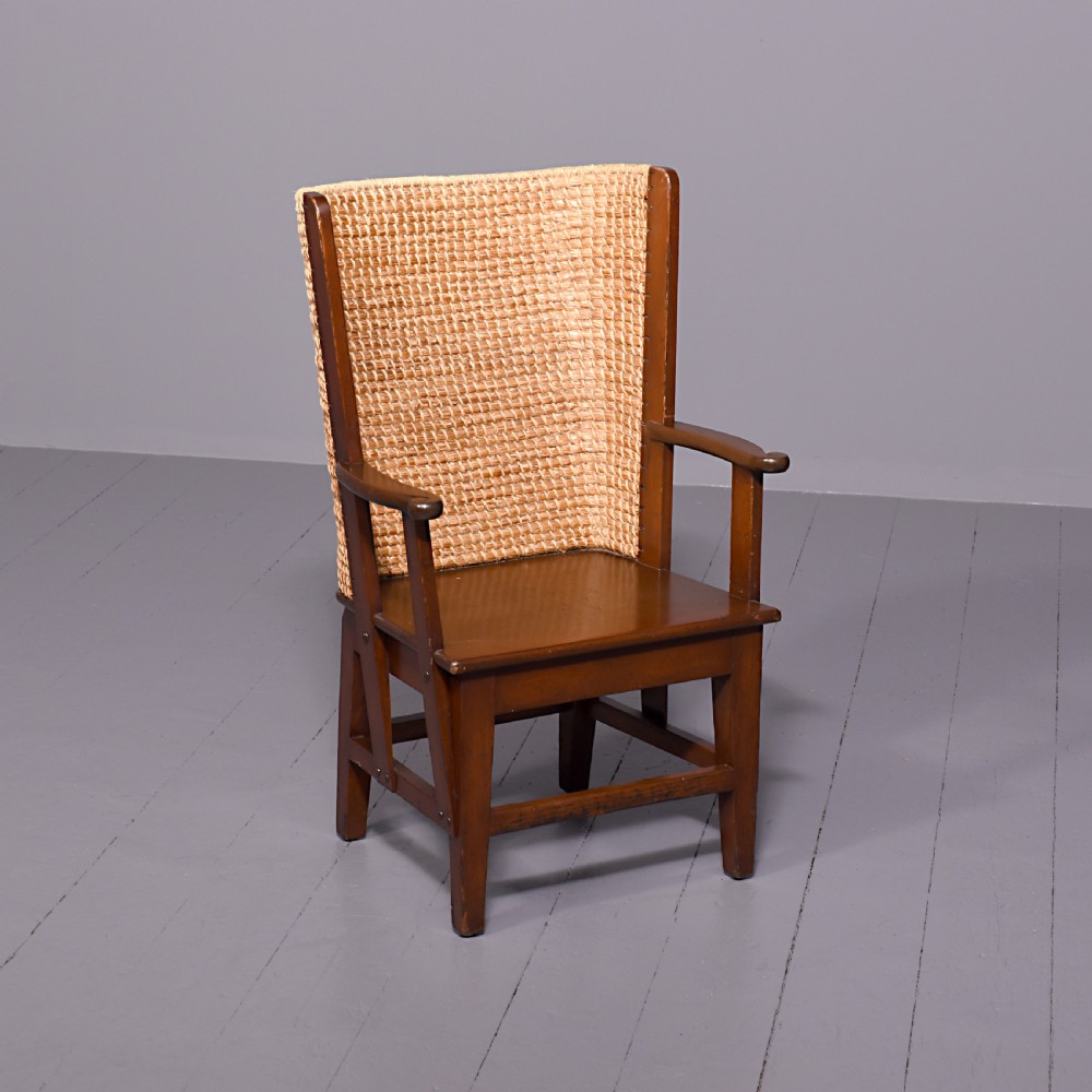 A stained beech wood armchair featuring a high curved backrest hand-woven from natural straw, a flat wooden seat, and open armrests.