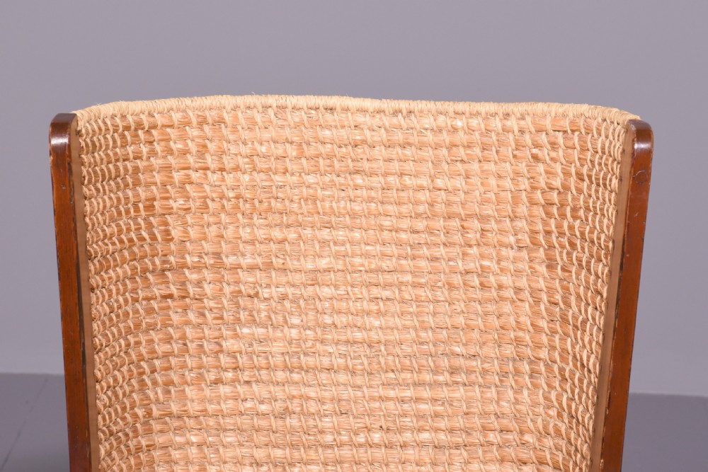 A stained beech wood armchair featuring a high curved backrest hand-woven from natural straw, a flat wooden seat, and open armrests. View III