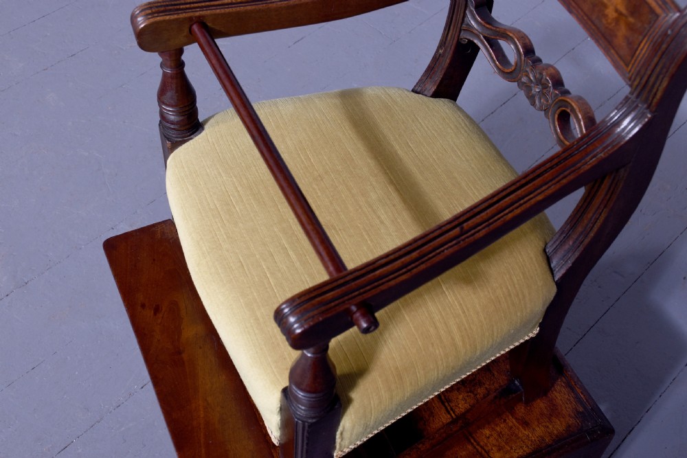 A George III mahogany childs high chair with a gold upholstered seat, safety bar, and footrest, resting atop a matching wooden stand. View V