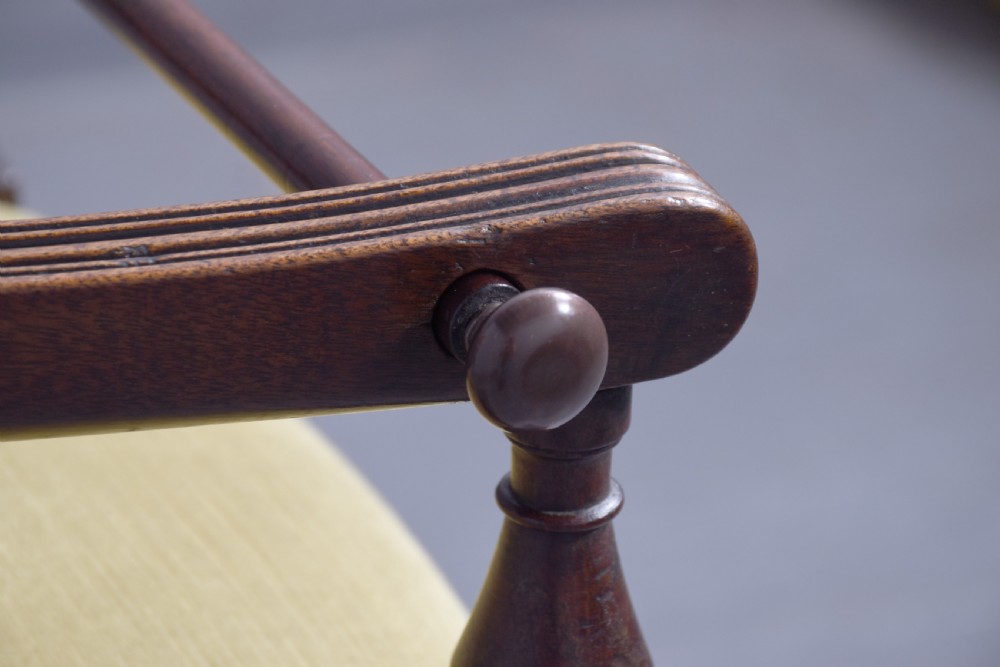 A George III mahogany childs high chair with a gold upholstered seat, safety bar, and footrest, resting atop a matching wooden stand. View VI