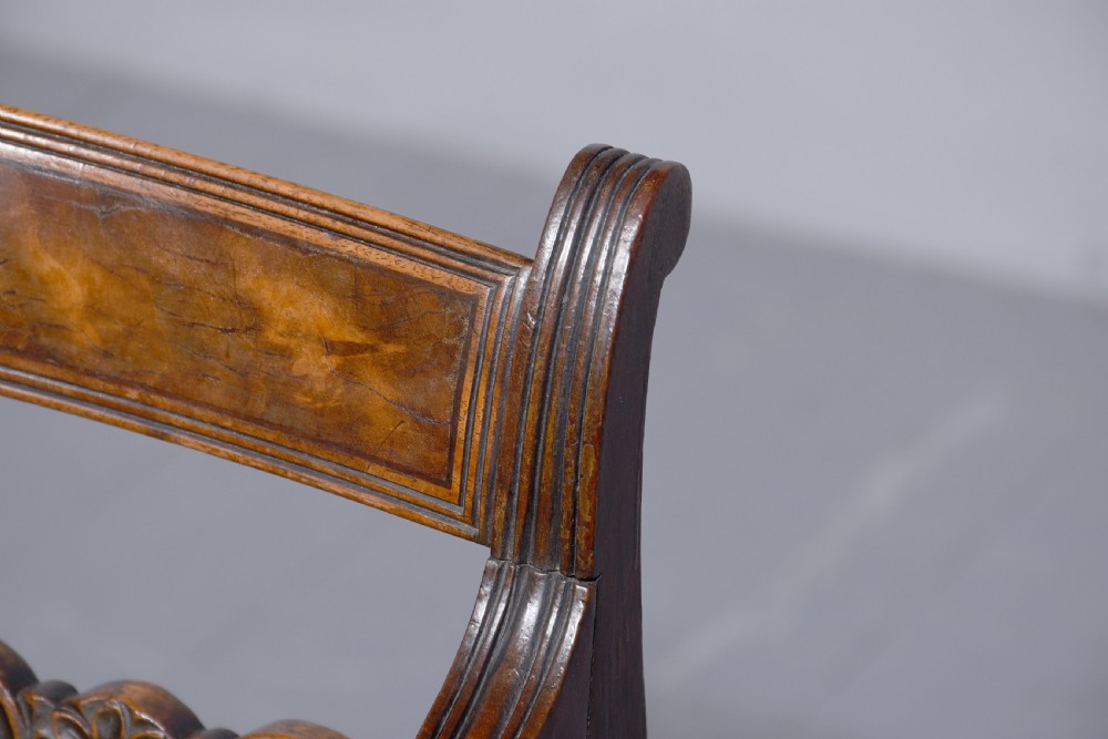 A George III mahogany childs high chair with a gold upholstered seat, safety bar, and footrest, resting atop a matching wooden stand. View VII