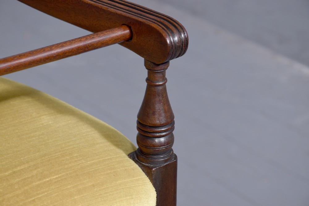 A George III mahogany childs high chair with a gold upholstered seat, safety bar, and footrest, resting atop a matching wooden stand. View IX