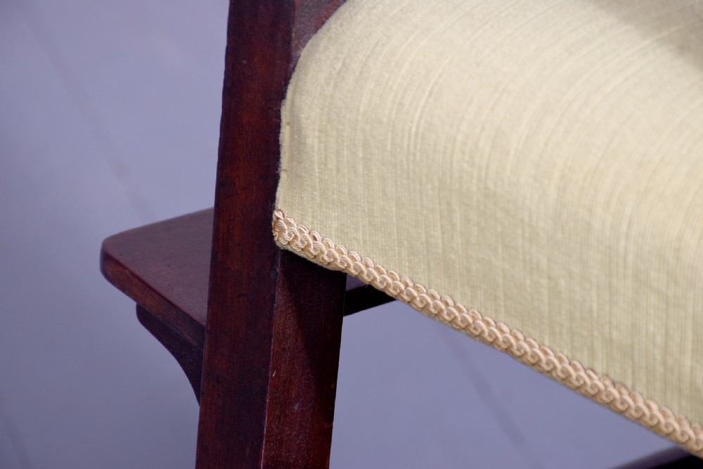 A George III mahogany childs high chair with a gold upholstered seat, safety bar, and footrest, resting atop a matching wooden stand. View X