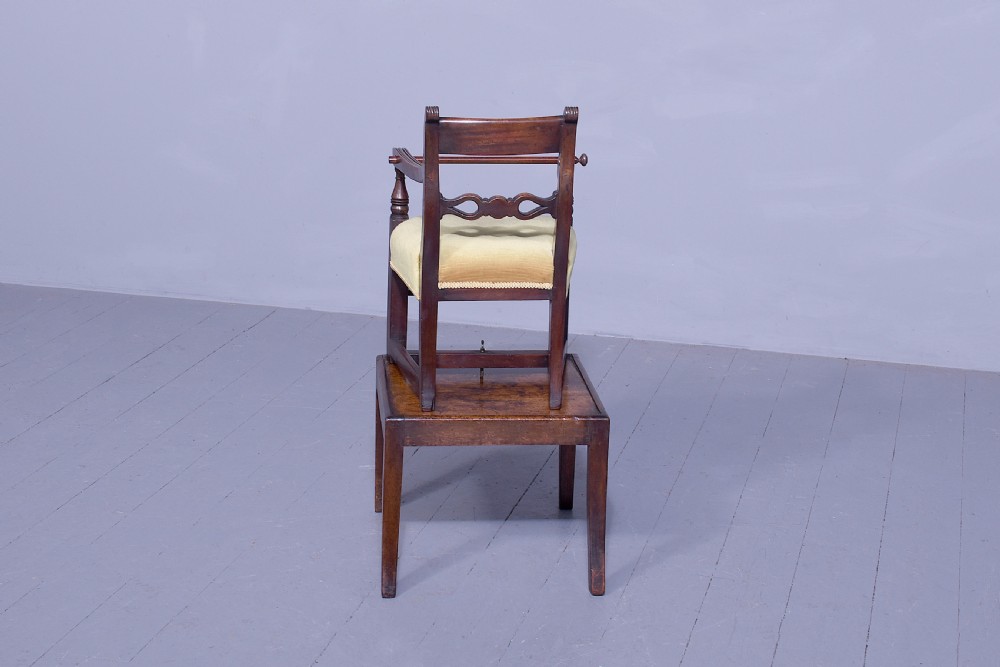 A George III mahogany childs high chair with a gold upholstered seat, safety bar, and footrest, resting atop a matching wooden stand. View XI