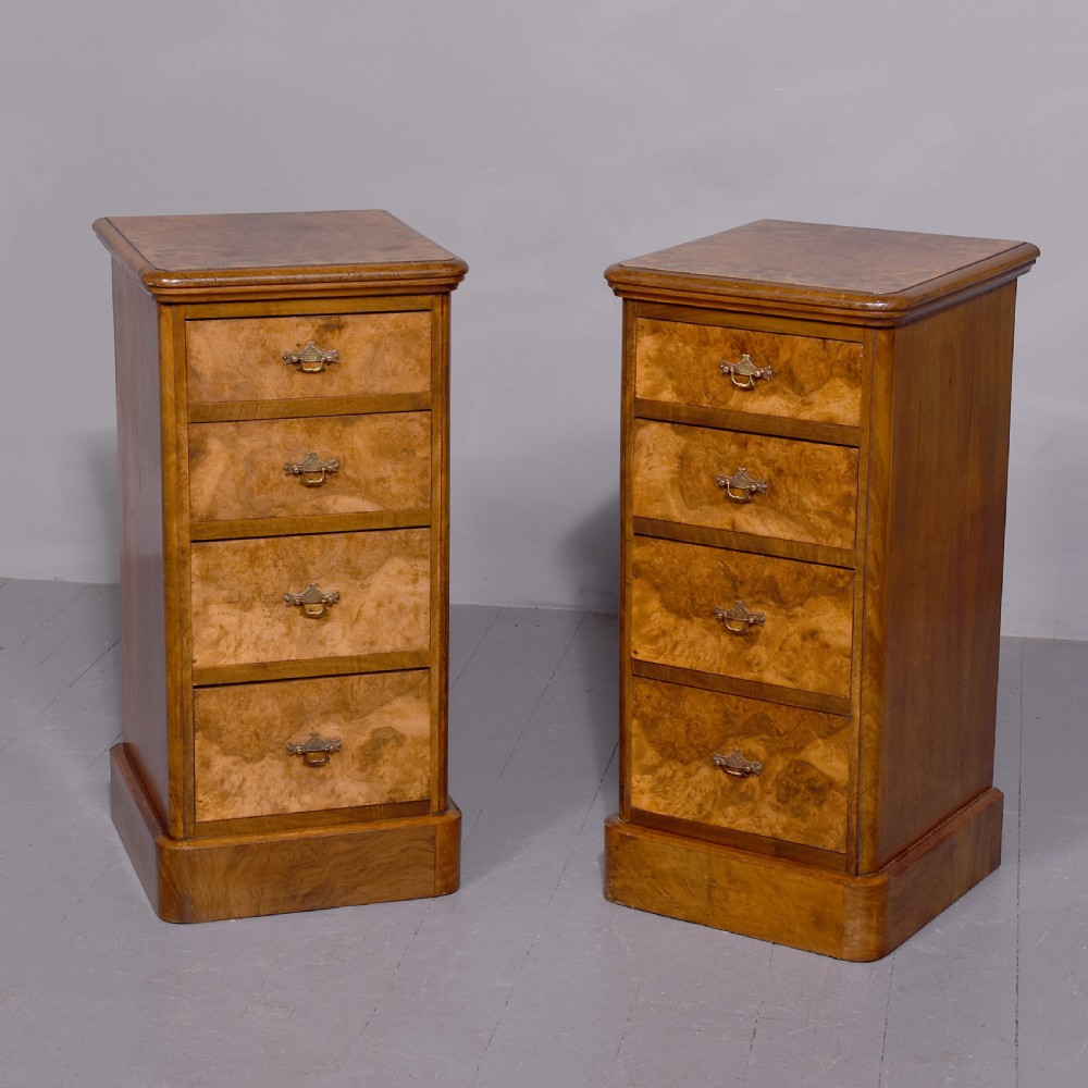 A pair of late Victorian burr walnut small chests of drawers featuring four drawers each with brass handles and plinth bases.