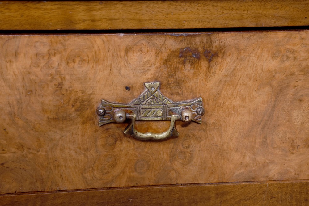 A pair of late Victorian burr walnut small chests of drawers featuring four drawers each with brass handles and plinth bases. View II