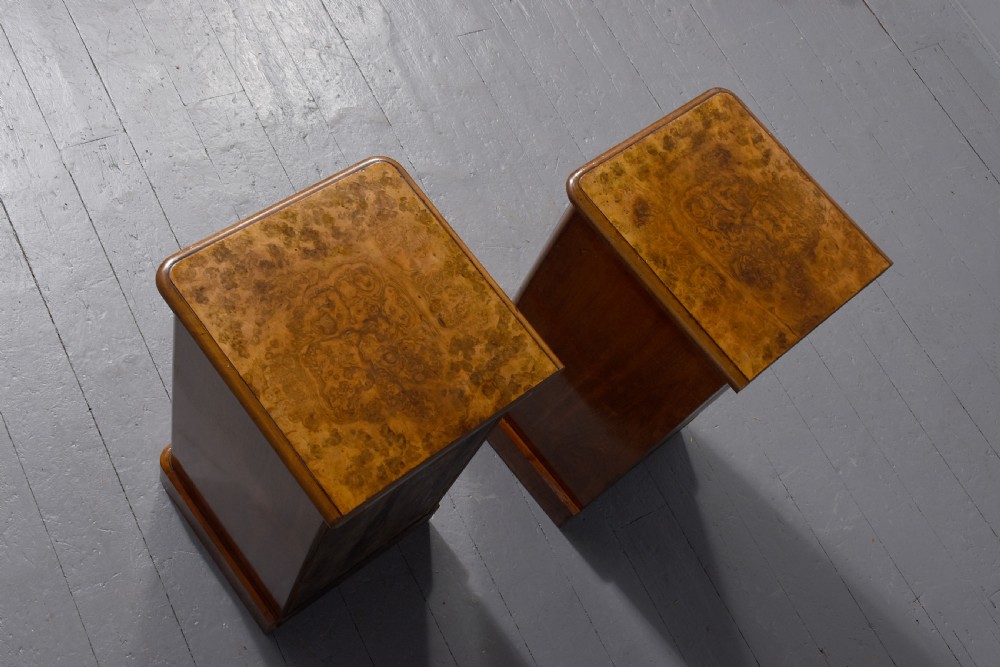 A pair of late Victorian burr walnut small chests of drawers featuring four drawers each with brass handles and plinth bases. View V