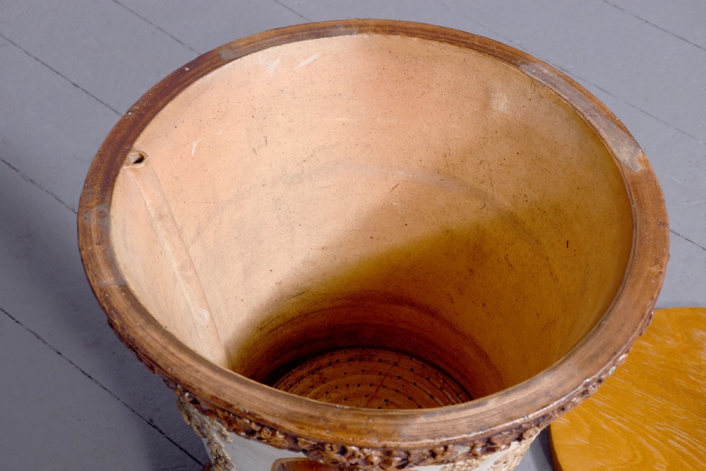 A Victorian glazed stoneware water filter urn decorated with relief crest motifs, floral borders, side handles, and a fitted wooden lid. View IV