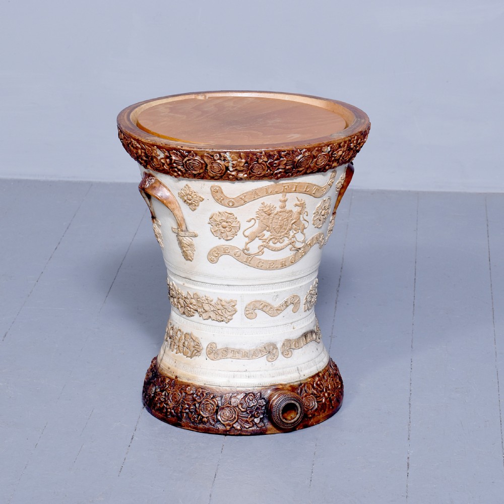 A Victorian glazed stoneware water filter urn decorated with relief crest motifs, floral borders, side handles, and a fitted wooden lid. View VI