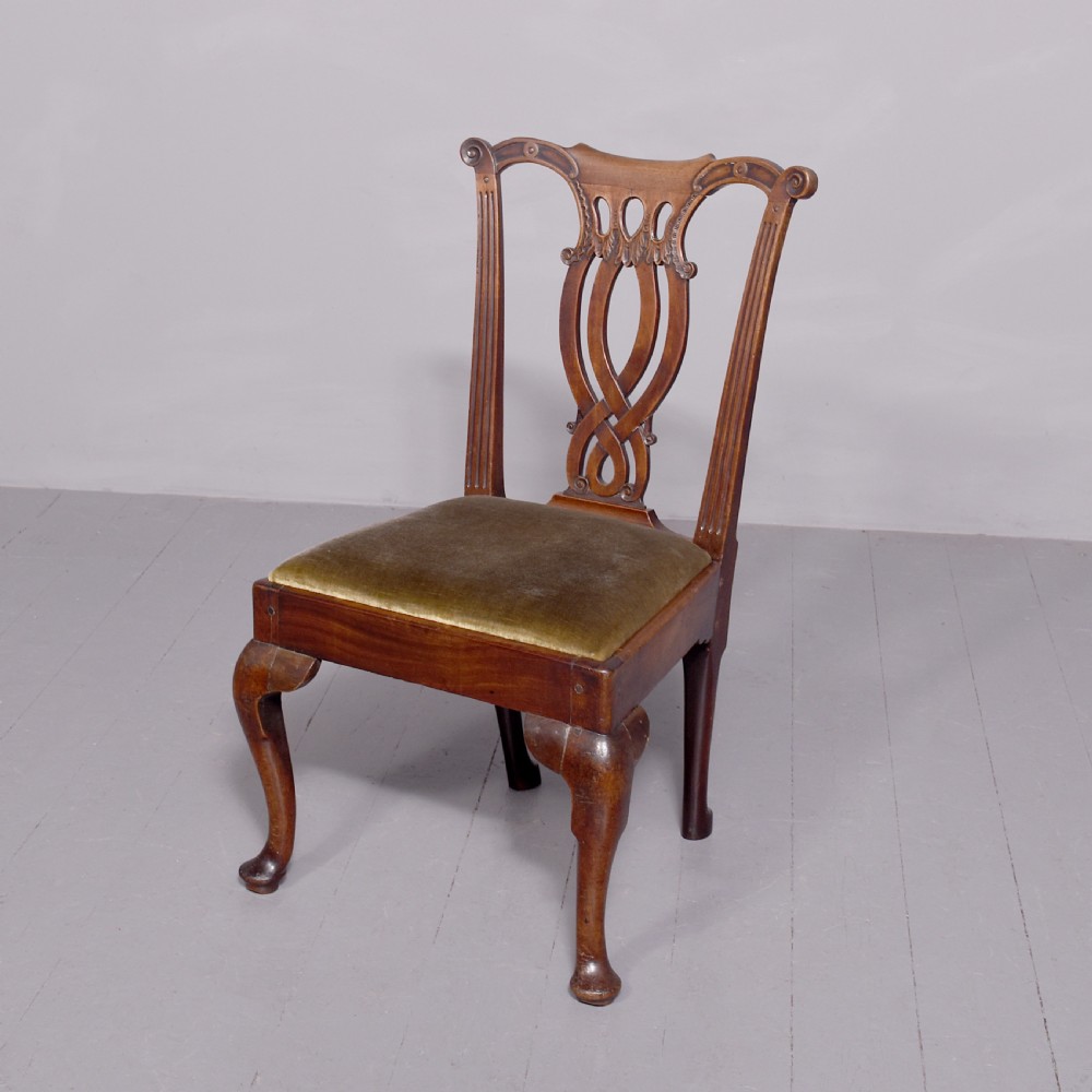 A George II carved mahogany side chair featuring a pierced strapwork splat back, green velvet seat, and cabriole front legs with pad feet.