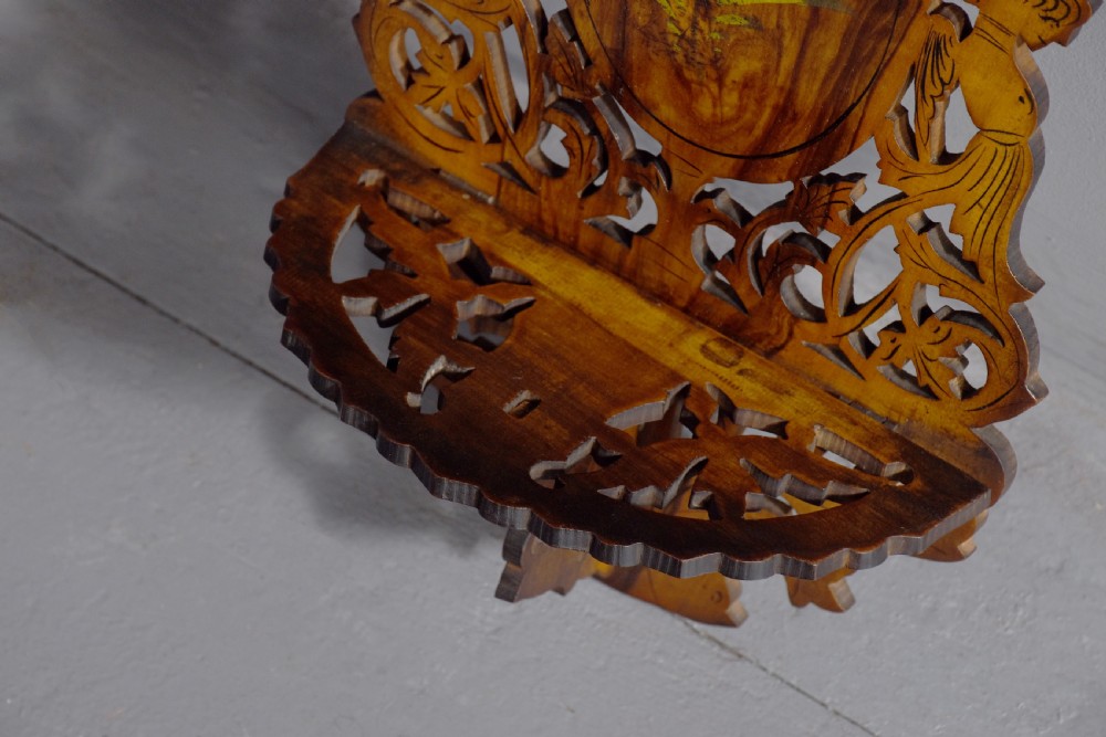 A pair of carved brown wooden wall brackets featuring pierced fretwork, foliage motifs, and oval central panels with painted floral designs. View IV