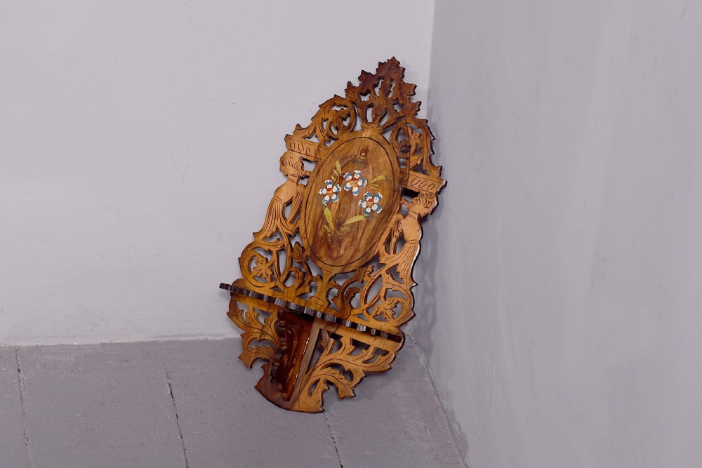 A pair of carved brown wooden wall brackets featuring pierced fretwork, foliage motifs, and oval central panels with painted floral designs. View V