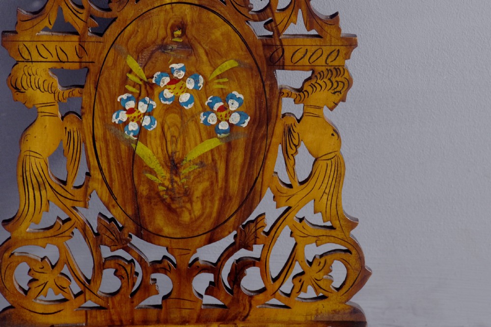 A pair of carved brown wooden wall brackets featuring pierced fretwork, foliage motifs, and oval central panels with painted floral designs. View VI