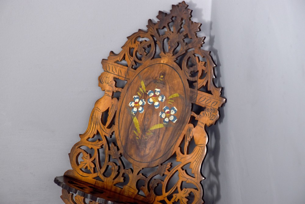A pair of carved brown wooden wall brackets featuring pierced fretwork, foliage motifs, and oval central panels with painted floral designs. View VII