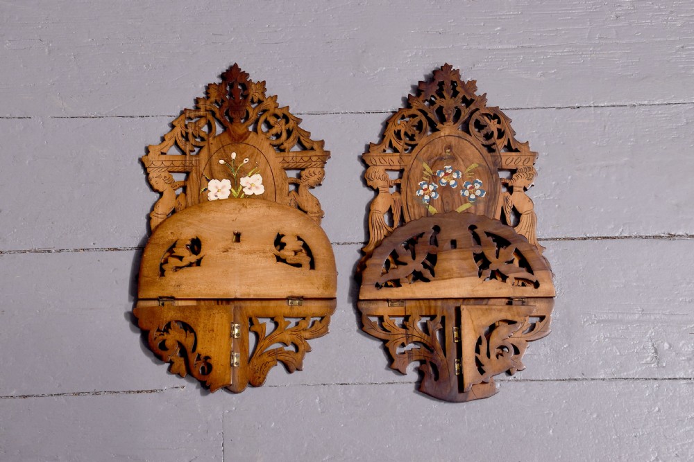 A pair of carved brown wooden wall brackets featuring pierced fretwork, foliage motifs, and oval central panels with painted floral designs. View VIII