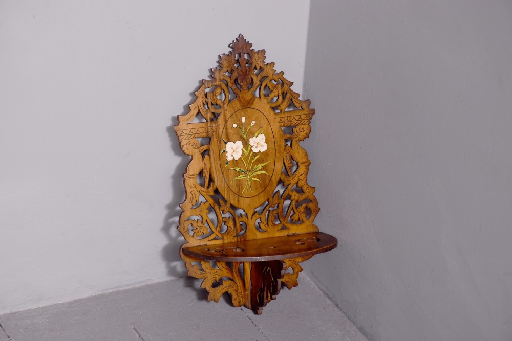 A pair of carved brown wooden wall brackets featuring pierced fretwork, foliage motifs, and oval central panels with painted floral designs. View X