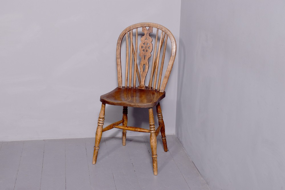A set of four antique wooden Windsor dining chairs featuring hoop backs, pierced wheelback splats, shaped seats, and turned legs. View II