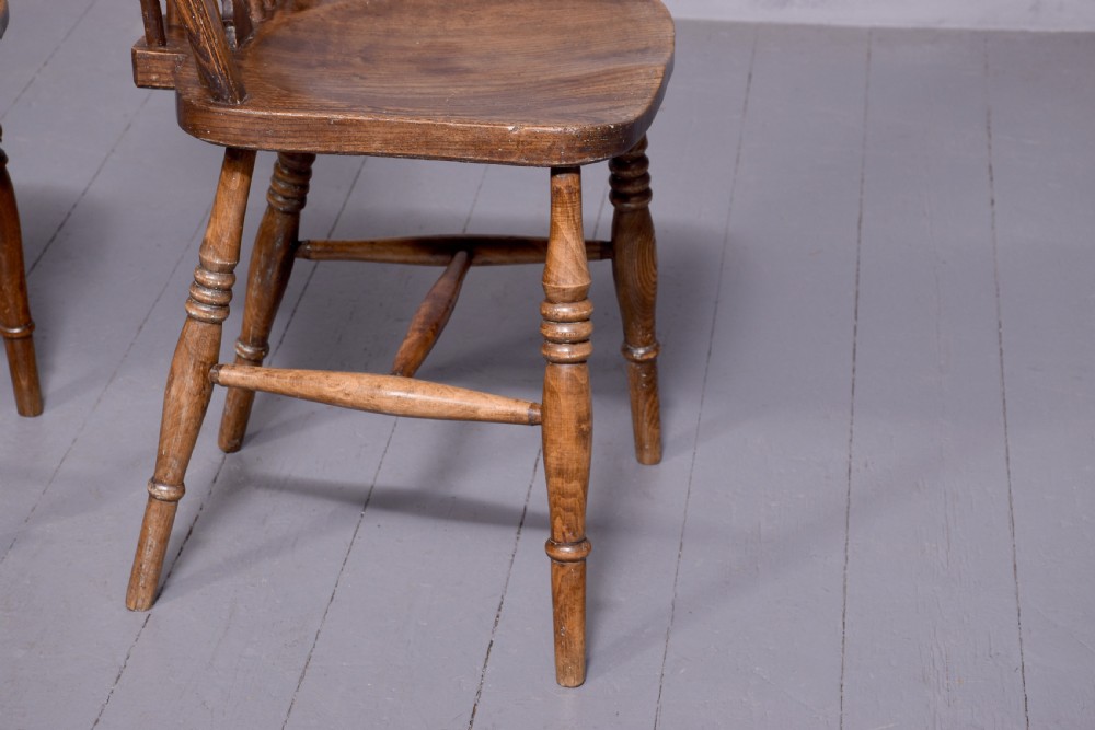A set of four antique wooden Windsor dining chairs featuring hoop backs, pierced wheelback splats, shaped seats, and turned legs. View III