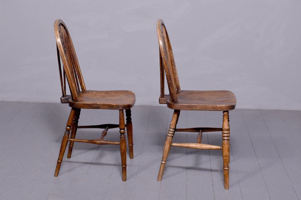 A set of four antique wooden Windsor dining chairs featuring hoop backs, pierced wheelback splats, shaped seats, and turned legs. View IV