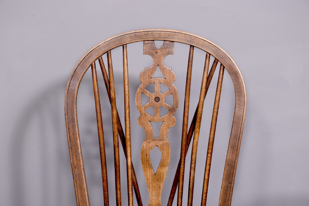 A set of four antique wooden Windsor dining chairs featuring hoop backs, pierced wheelback splats, shaped seats, and turned legs. View V
