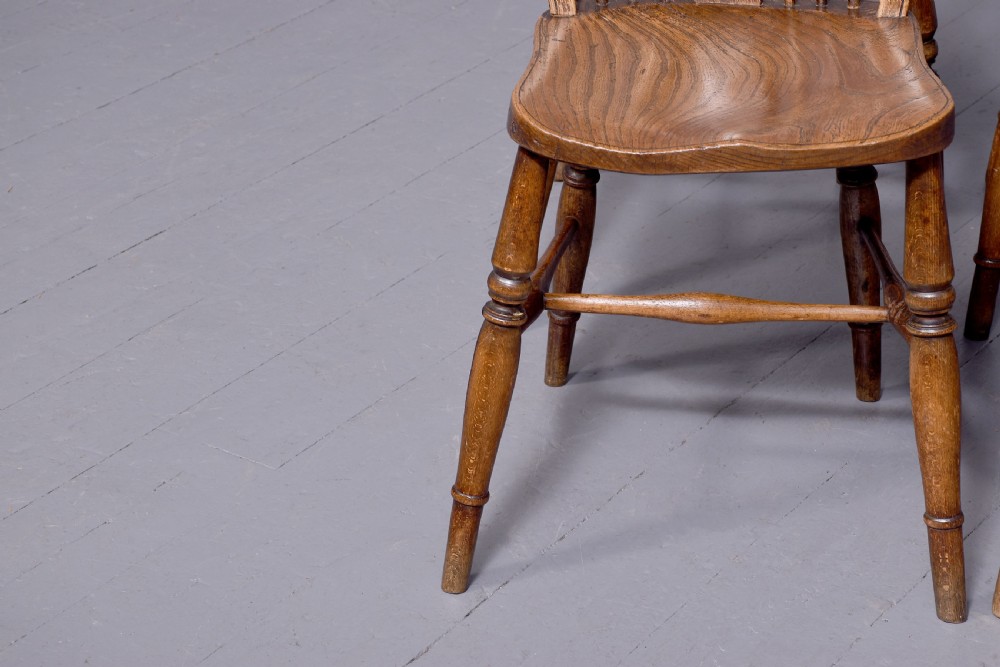A set of four antique wooden Windsor dining chairs featuring hoop backs, pierced wheelback splats, shaped seats, and turned legs. View VI