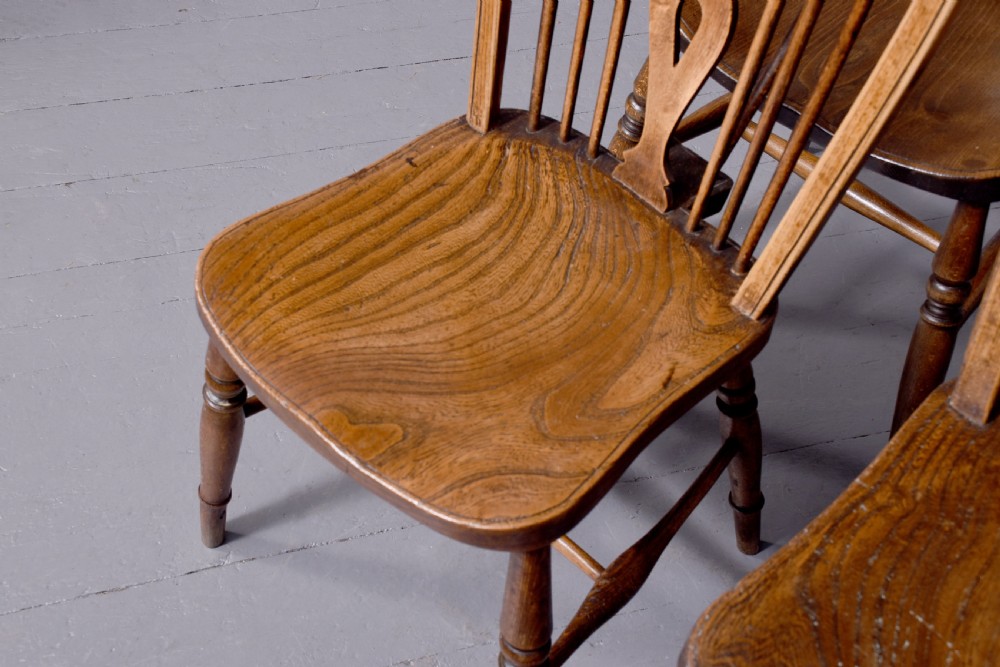 A set of four antique wooden Windsor dining chairs featuring hoop backs, pierced wheelback splats, shaped seats, and turned legs. View VII