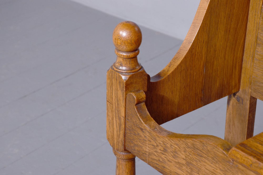 An antique oak Art Nouveau hall stand featuring a central mirror, brass coat hooks, a small shelf compartment, and a lower umbrella stand base. View VI