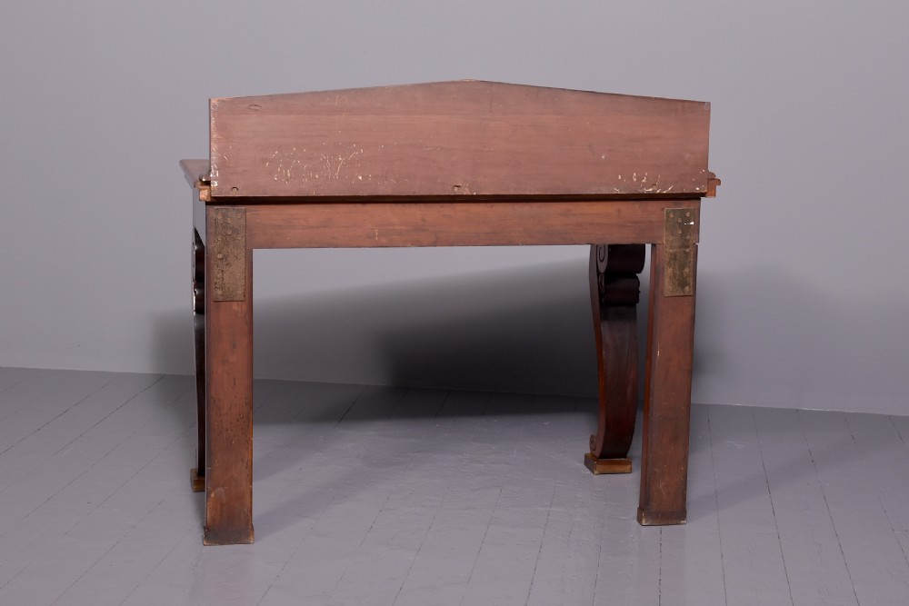 A William IV mahogany console table featuring a pedimented upstand, flame mahogany frieze, and acanthus leaf carved scroll front legs resting on plinth bases. View VII