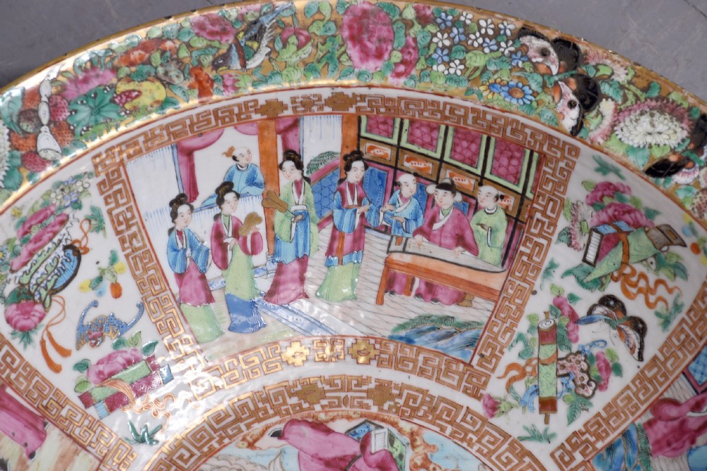 A large round Canton Famille Rose porcelain bowl decorated inside with hand-painted Mandarin figure scenes, floral borders, and gilded rims. View V
