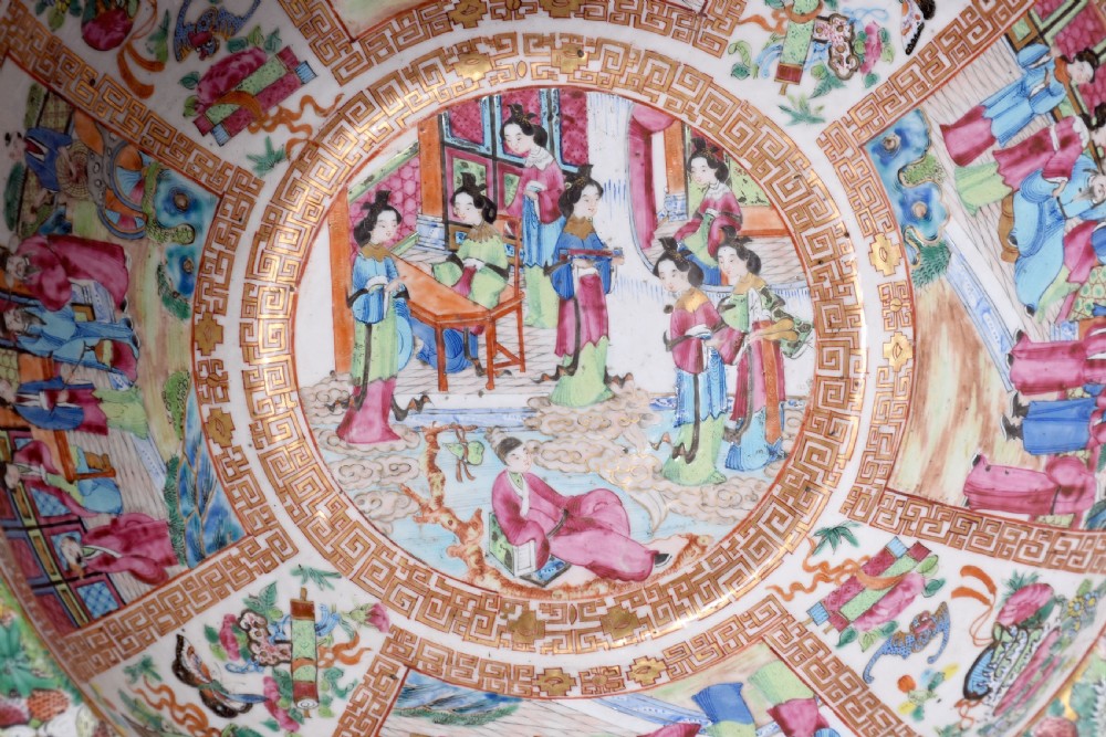 A large round Canton Famille Rose porcelain bowl decorated inside with hand-painted Mandarin figure scenes, floral borders, and gilded rims. View VI